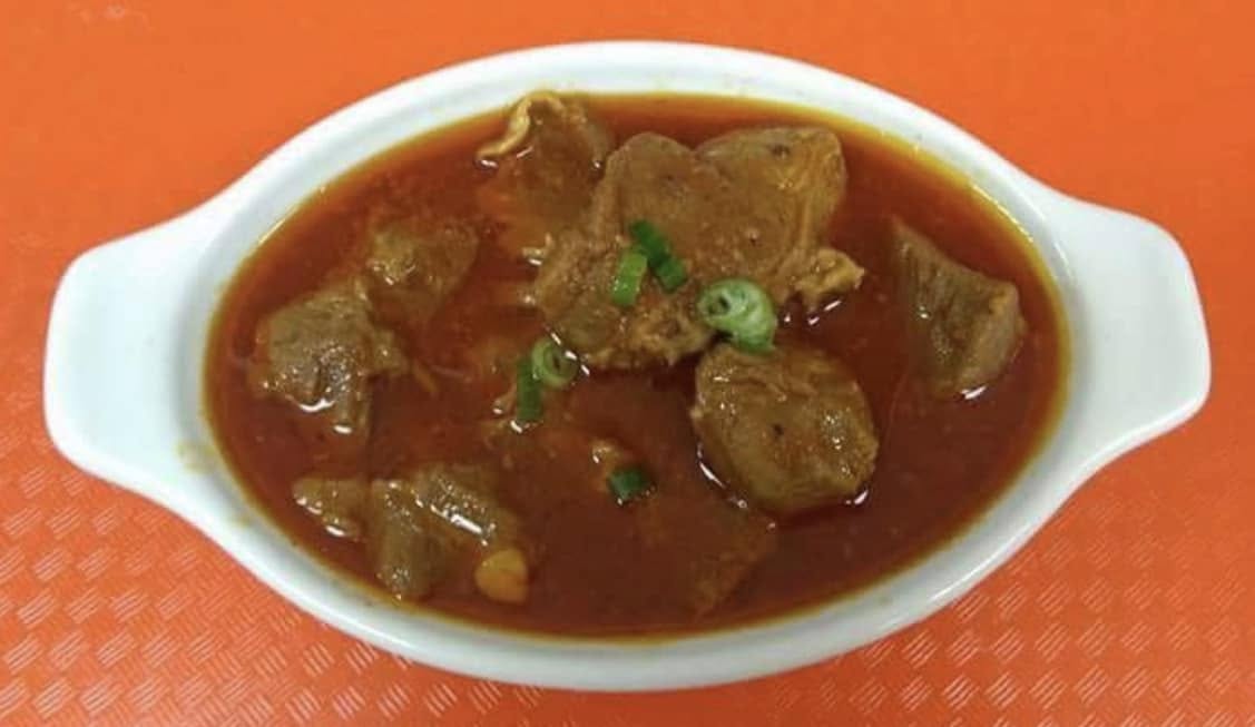 Beef korma in a white oval dish garnished with green chili
